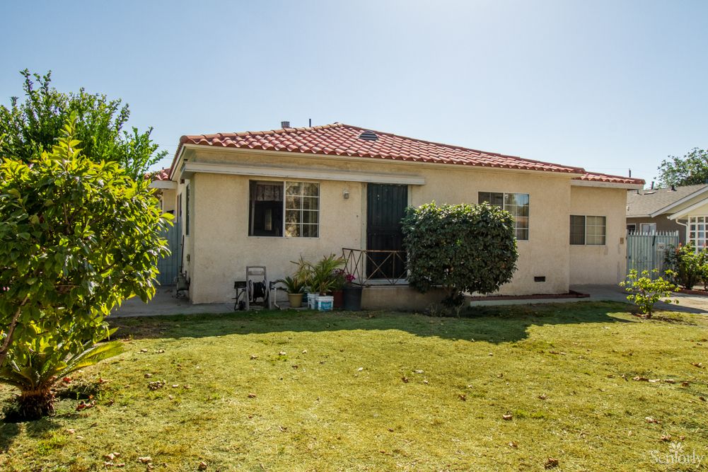 A small house with a tidy backyard on a sunny day.