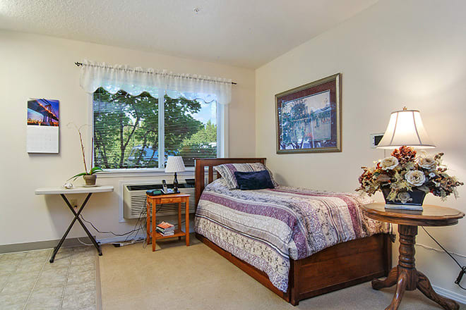 A cozy bedroom with a single bed, desk, and window view.