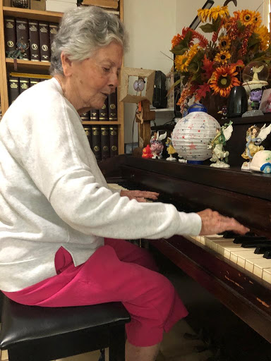 An elderly woman enjoying a moment of music at the piano.