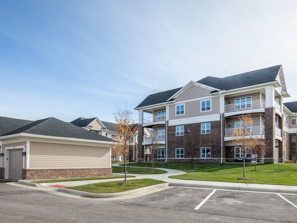 A modern apartment building with well-maintained landscaping and adjacent parking lot.
