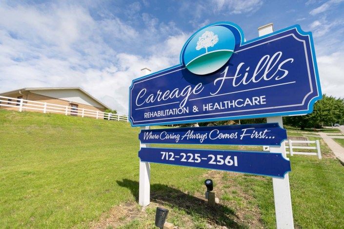 Sign for Careage Hills Rehabilitation & Healthcare facility against a grassy landscape.