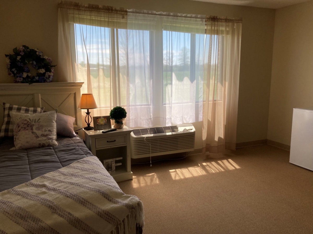 A cozy bedroom filled with natural light streaming through sheer curtains.