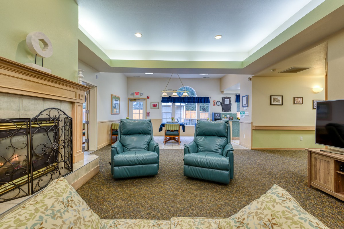 A cozy living room with two green recliner chairs facing a fireplace.