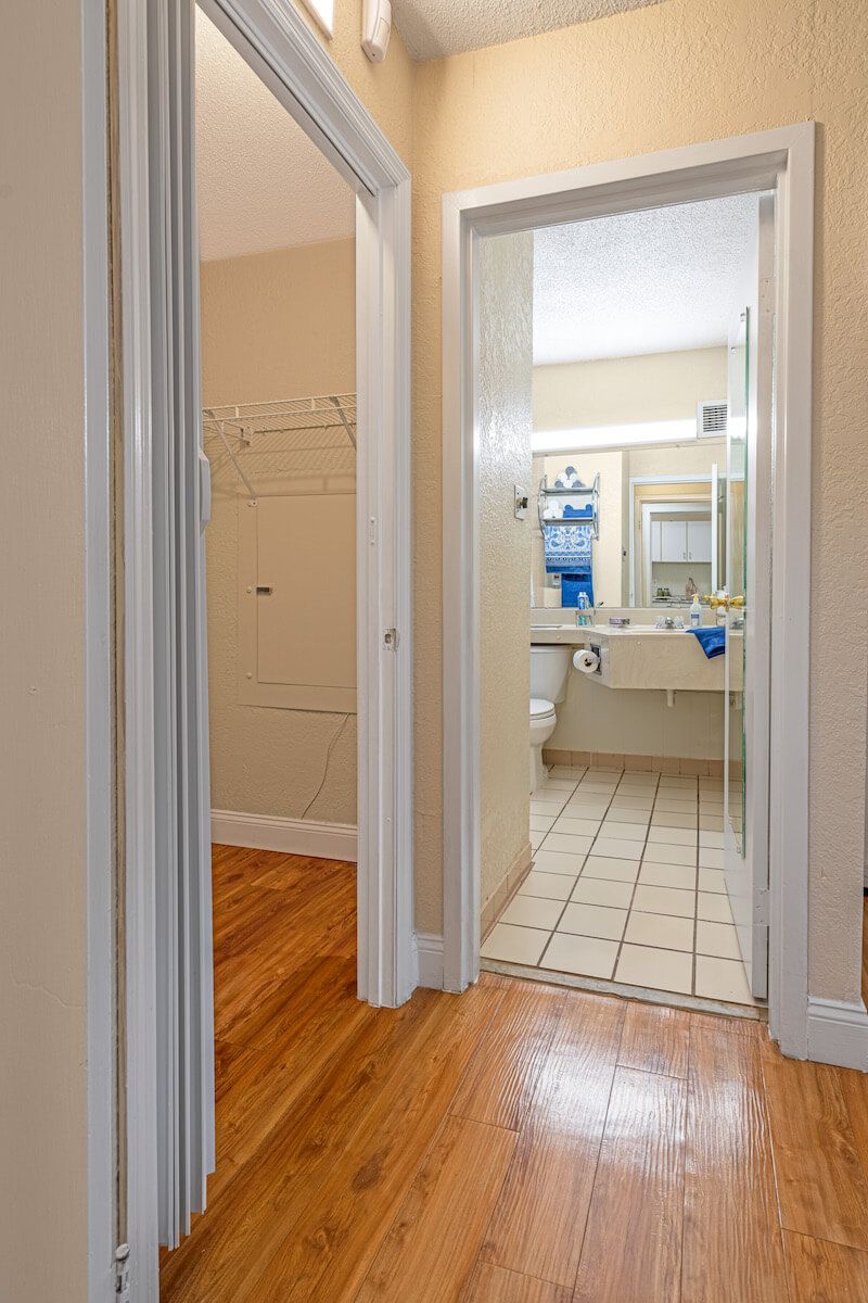 A view from a hallway into a bathroom featuring tiled floors and a sink with a mirror.
