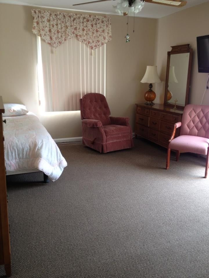 A cozy bedroom with a single bed, armchairs, and a dresser.
