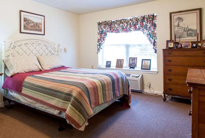 A cozy bedroom with a colorful striped bedspread and decorative window curtains.