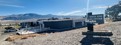 A modern building with a backdrop of mountains under a clear blue sky.