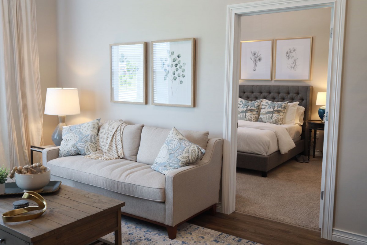 A cozy living room with a neutral-toned sofa and adjacent bedroom.