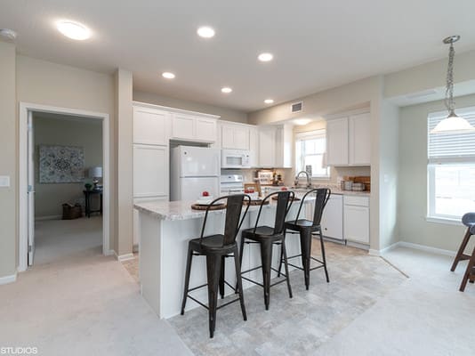A modern kitchen with white cabinets and bar stools at the countertop.