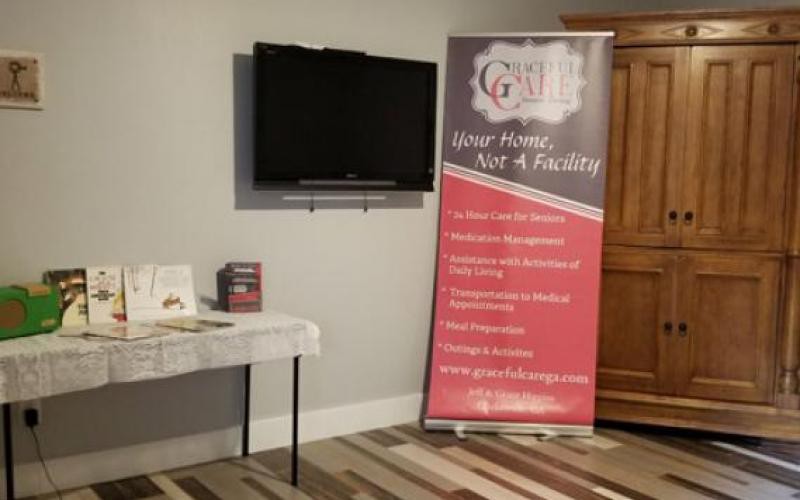 A promotional banner displayed next to a television and a small table indoors.