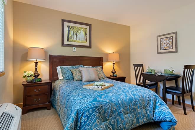 A cozy bedroom with a neatly made bed, bedside lamps, and decorative artwork.