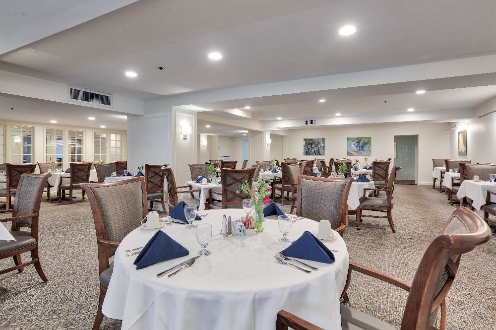 A spacious dining room with neatly arranged tables and elegant table settings.