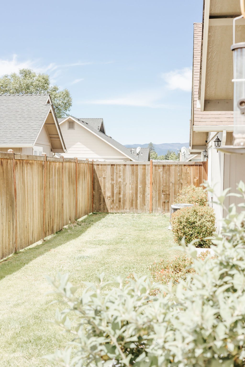 A sunny backyard with a wooden fence and neatly trimmed grass.
