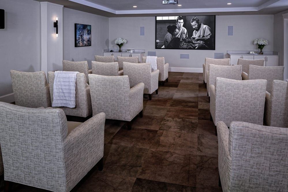 A stylish home theater with comfortable seating and a large projector screen displaying a black-and-white film.