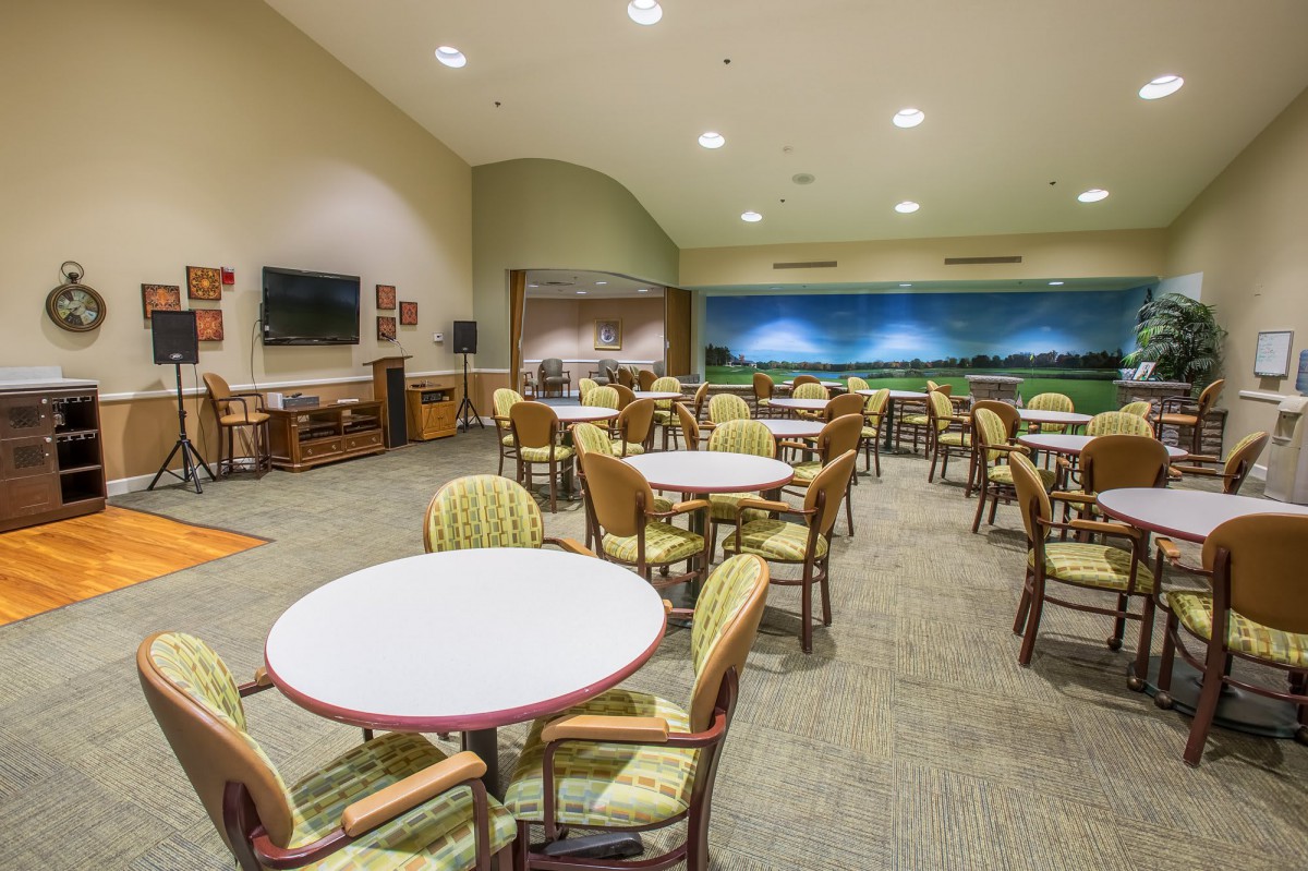 A spacious community room with multiple tables and chairs arranged for gatherings or meetings.