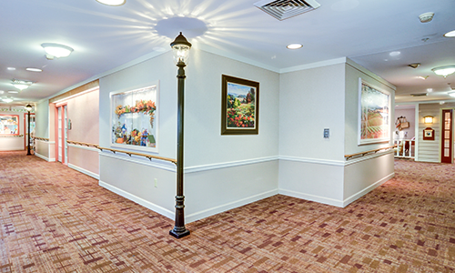 An indoor hallway featuring a decorative lamp post and paintings on the walls.