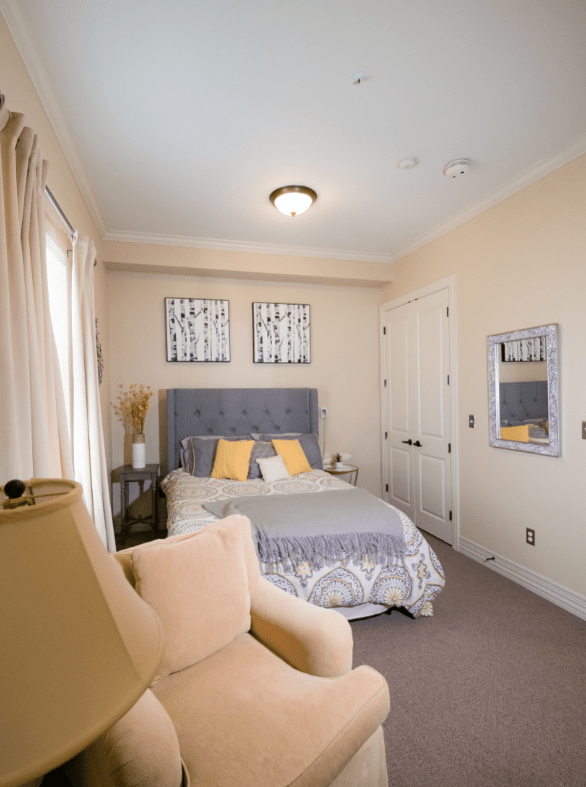 A cozy bedroom with a plush bed, decorated with cushions and a stylish chair.