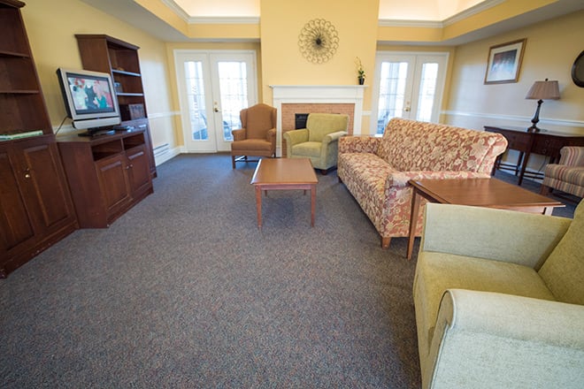 A cozy living room with sofas, a coffee table, and a television, centered around a fireplace.