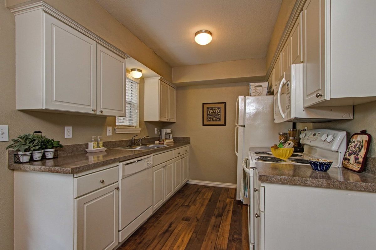 A cozy kitchen with white cabinets and wooden flooring.