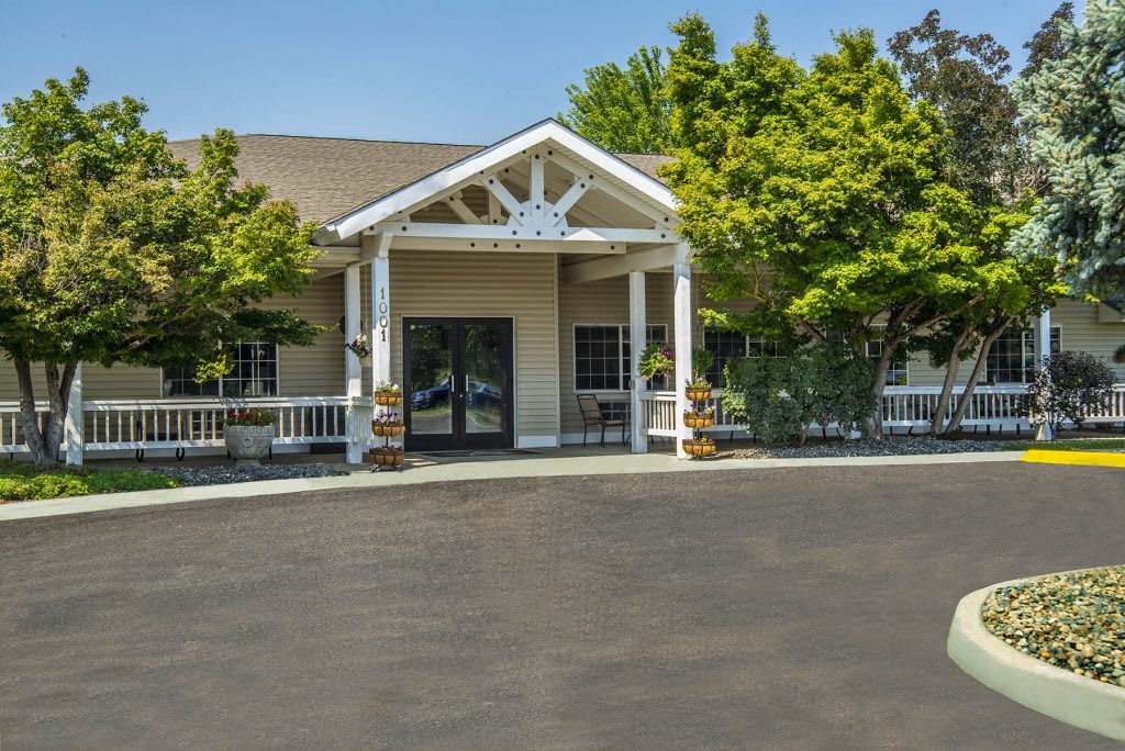 A well-maintained building entrance with a porch and surrounding trees.