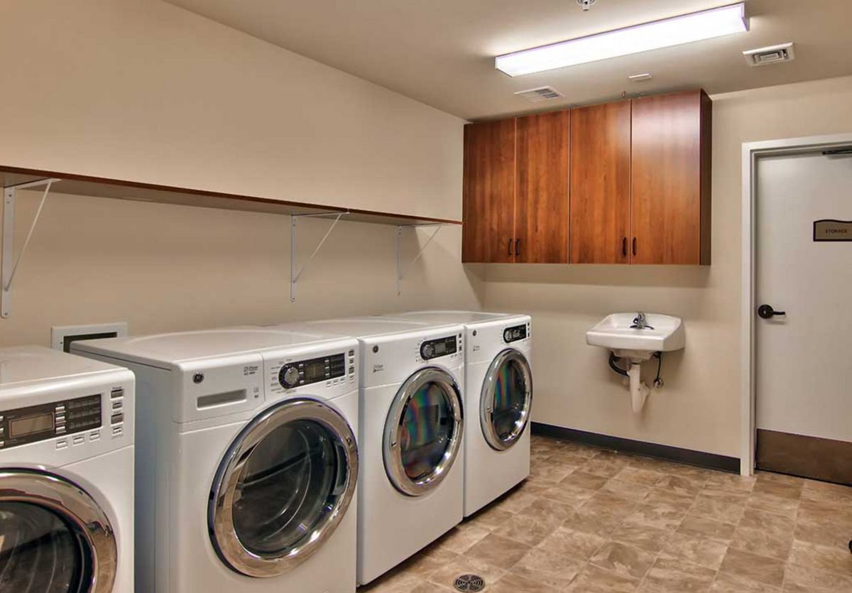 A well-organized laundry room with multiple washing machines and a sink.