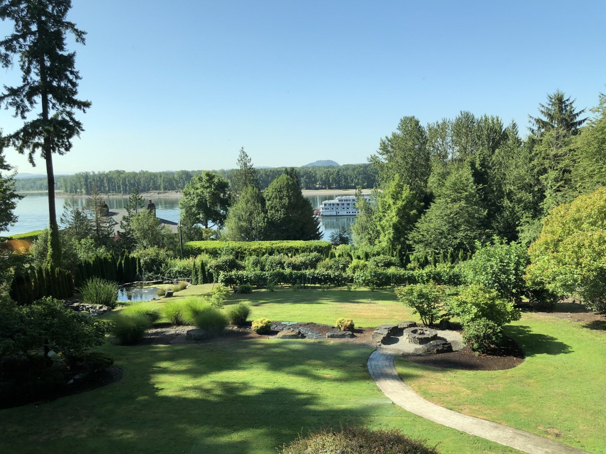 A tranquil garden view with lush greenery and a pathway, overlooking a marina.