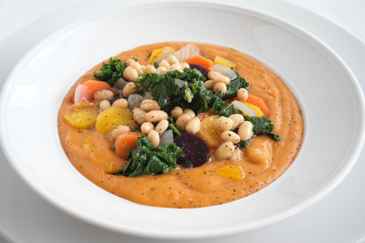 A bowl of creamy vegetable soup topped with chickpeas and kale.