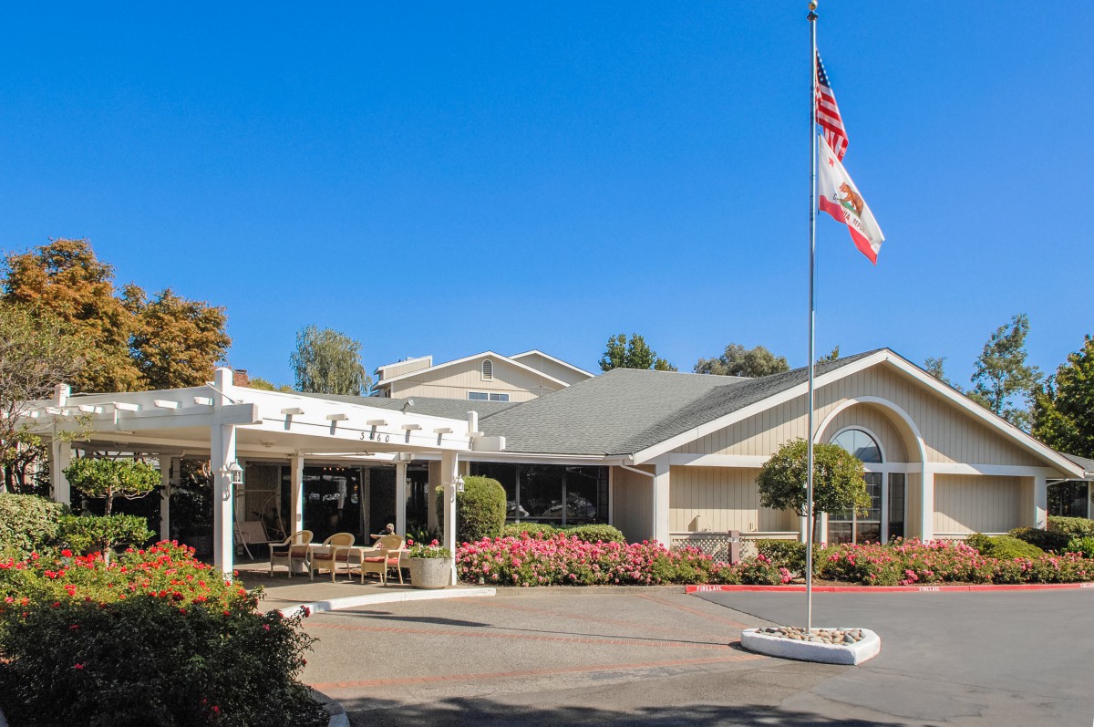 A building with a flagpole and garden in the foreground under a clear blue sky.