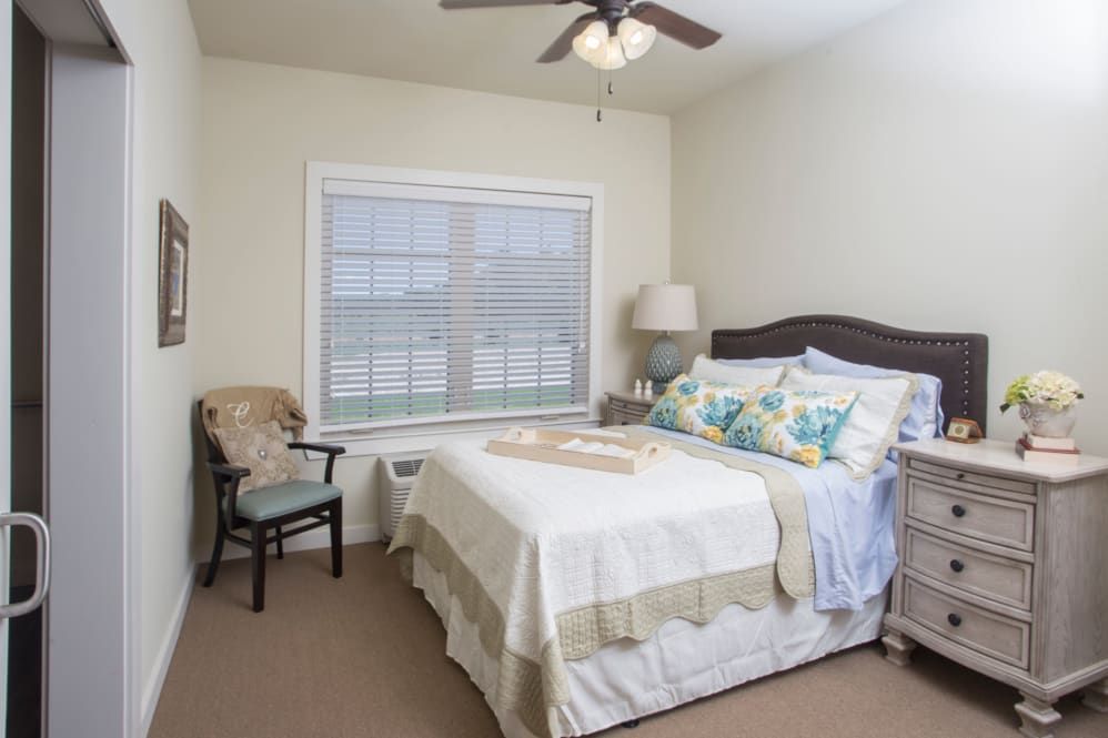 A cozy bedroom with a neatly made bed, decorative pillows, and a window providing natural light.
