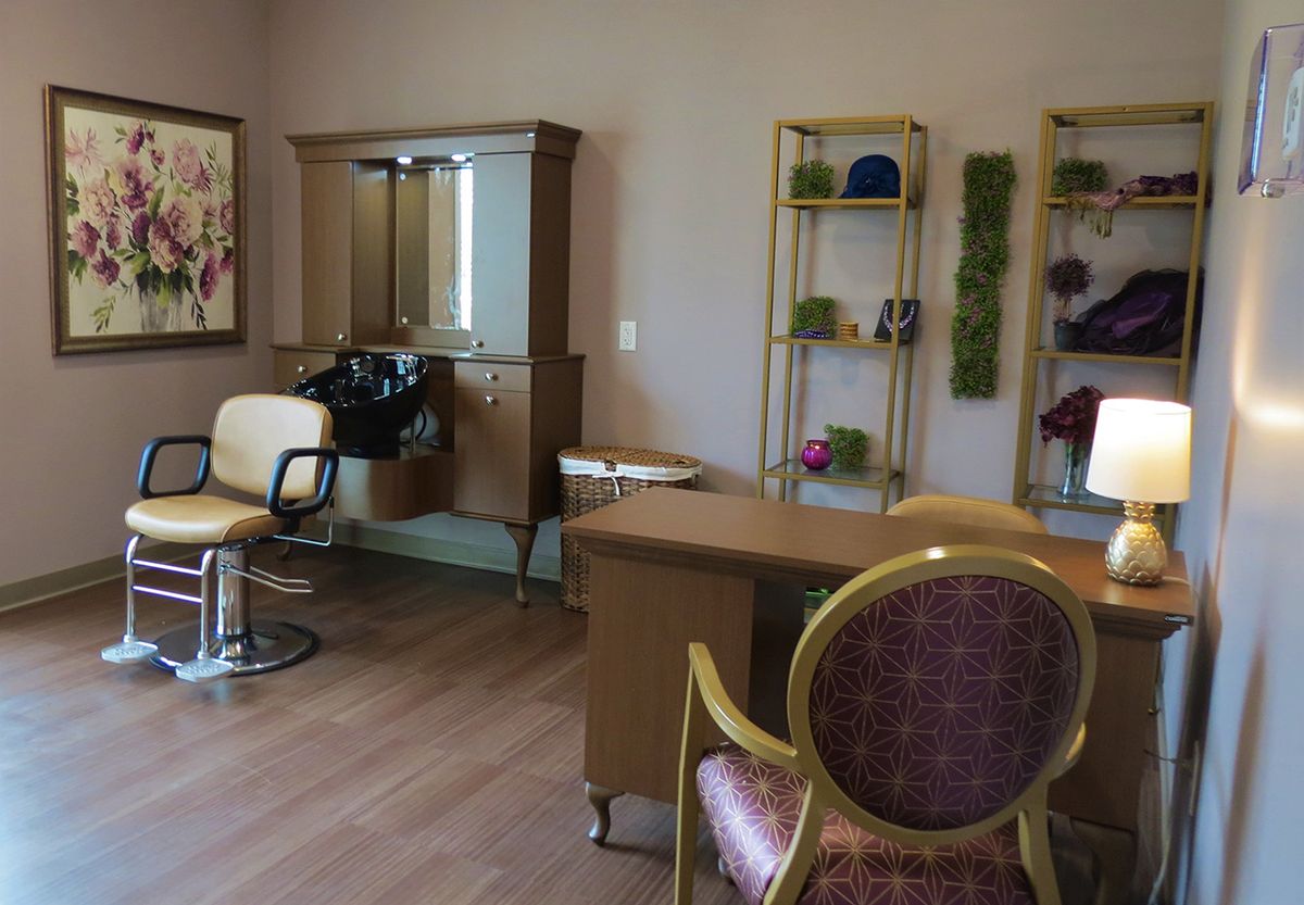 A cozy beauty salon interior with chairs, a mirror, and neatly organized shelves.