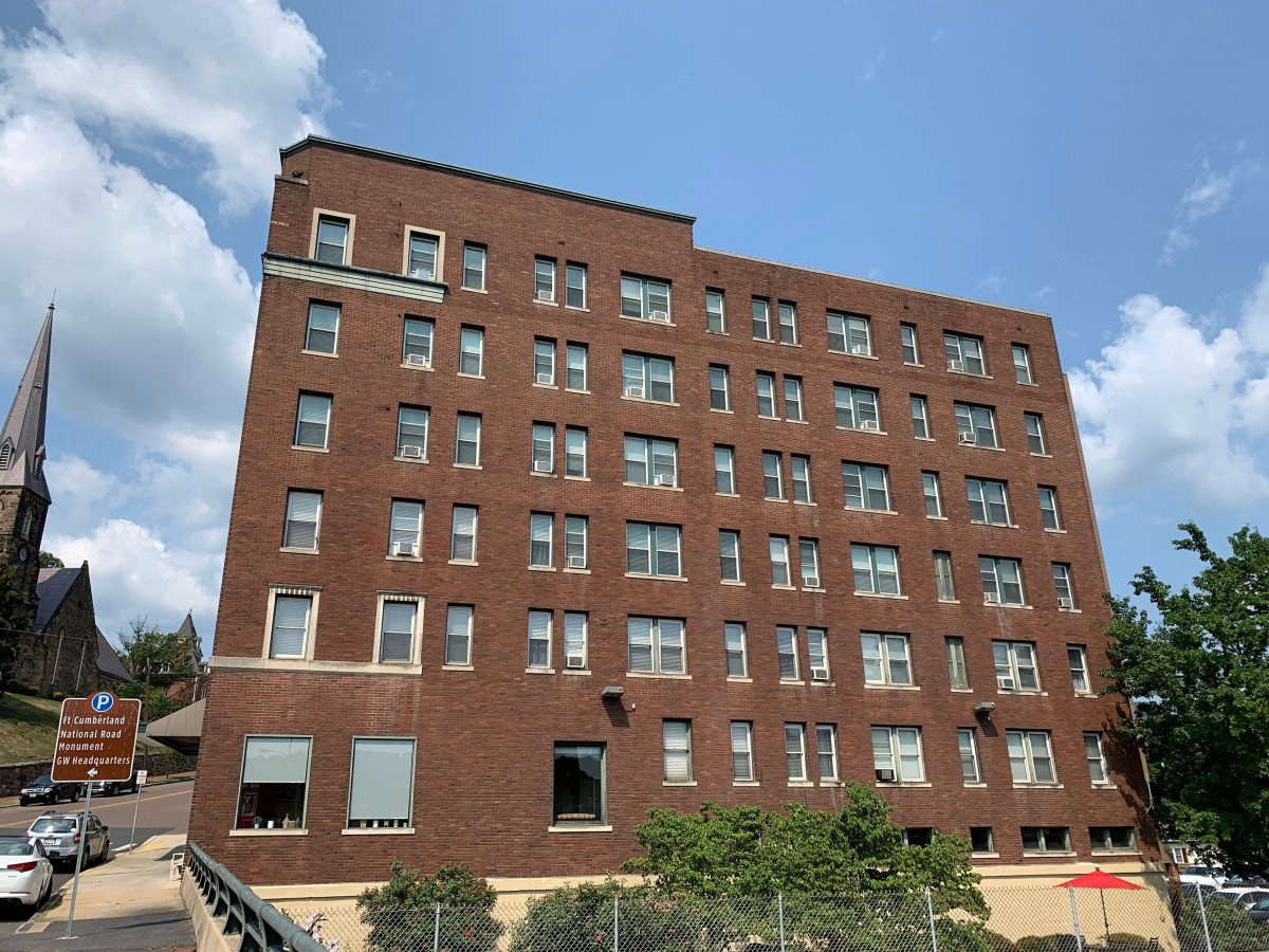 A multi-story brick building with numerous windows under a clear blue sky.