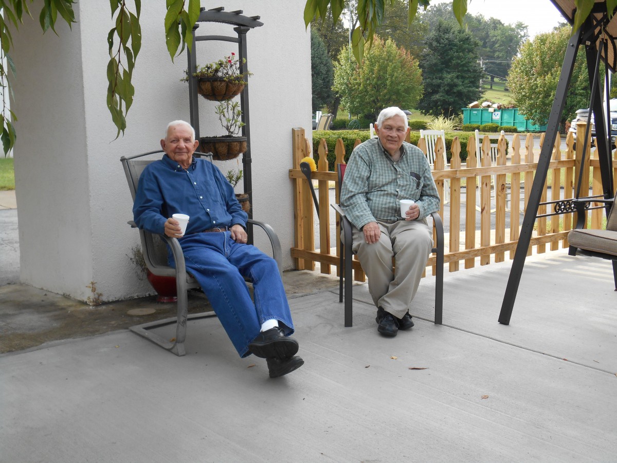 Two elderly men enjoying coffee on a patio.