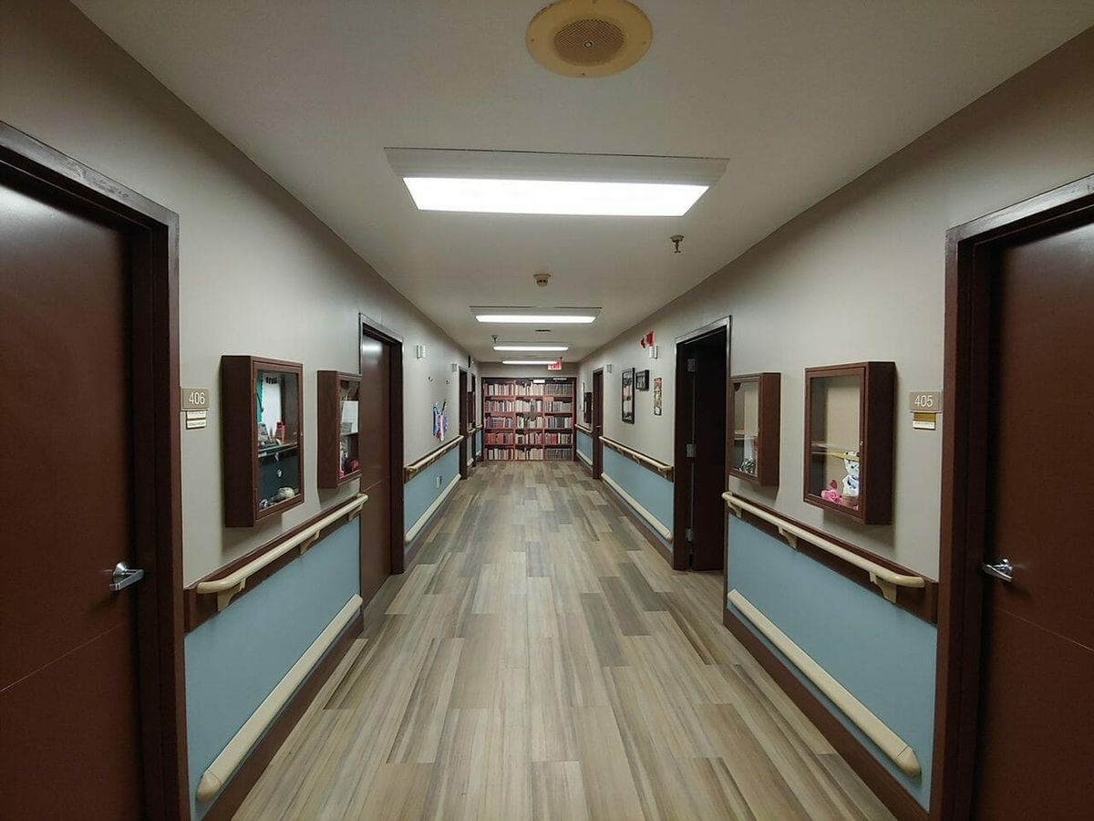 A long hallway with multiple doors and ceiling lights.
