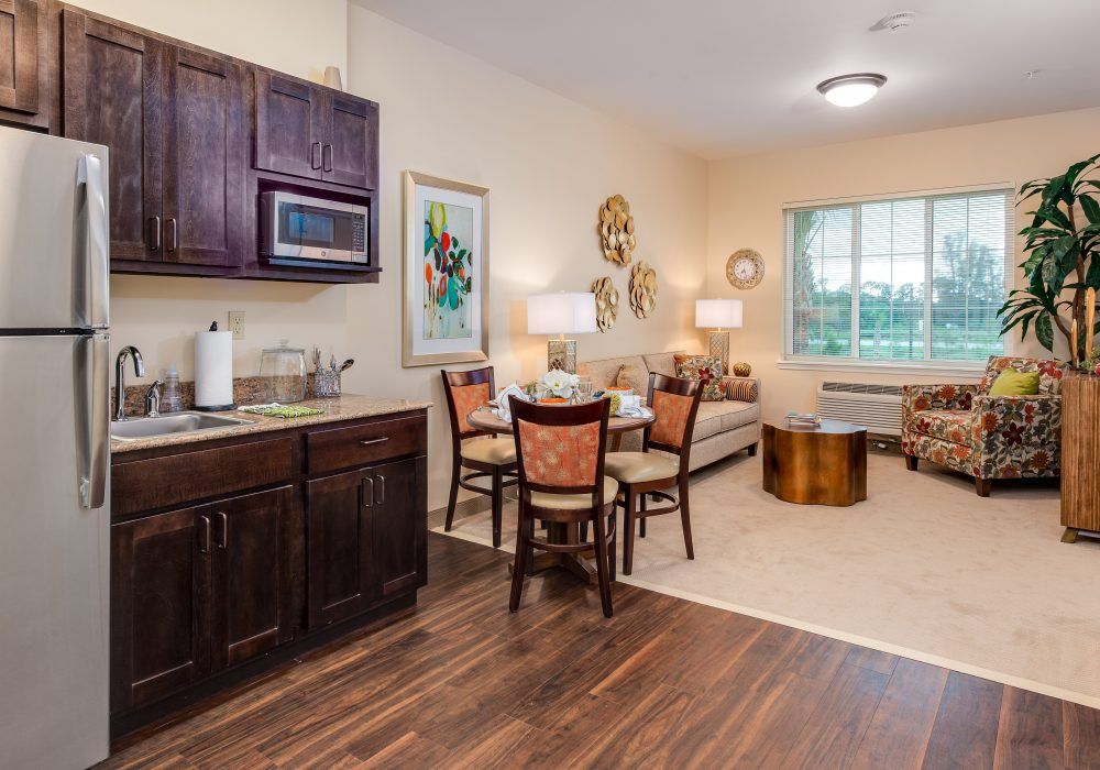 A modern apartment interior featuring a kitchen, dining, and living area with wood flooring.