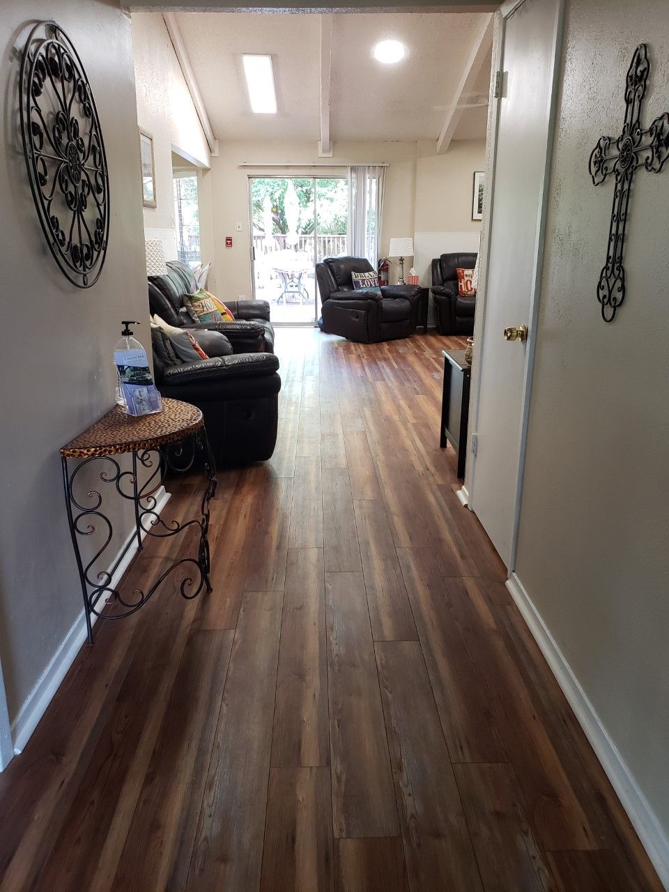 A view of a hallway leading to a living room with wooden flooring and comfortable seating.