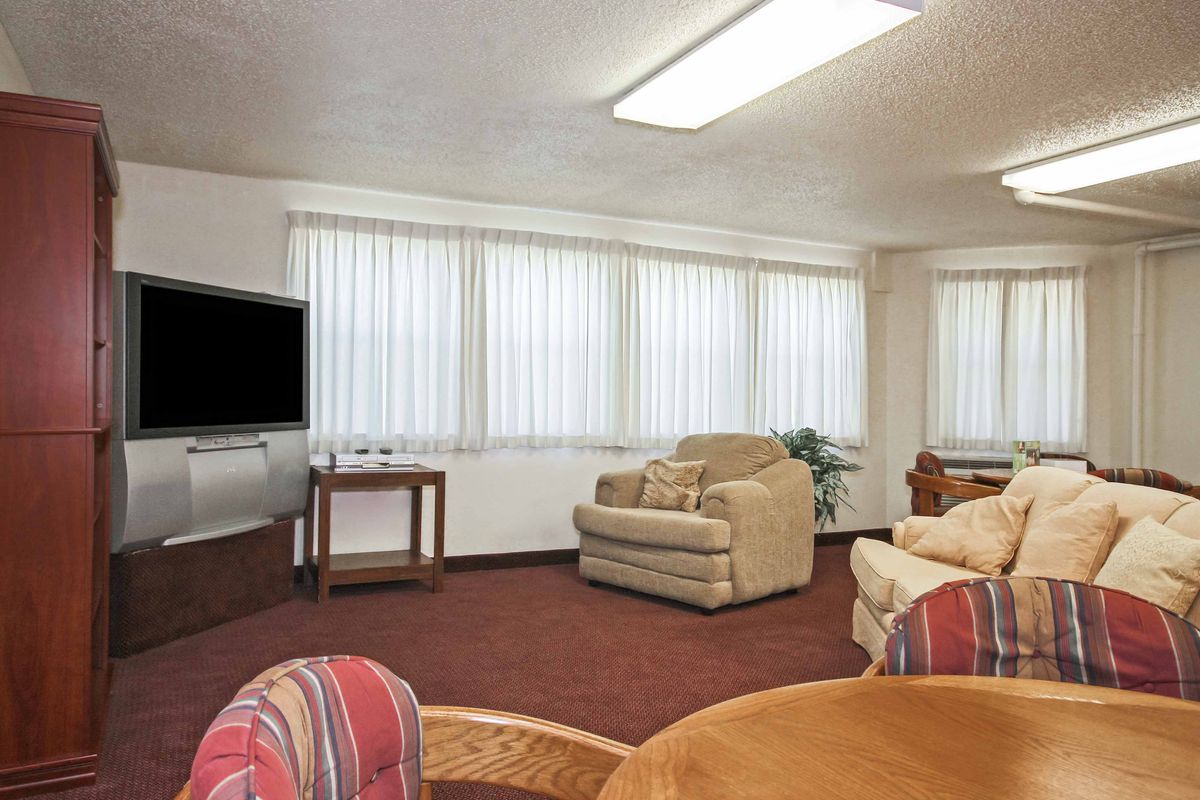 A cozy living room with comfortable seating, a large TV, and ample natural light streaming through the windows.