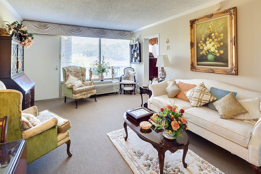 A cozy living room with classic decor featuring a sofa, armchairs, and a coffee table adorned with flowers.