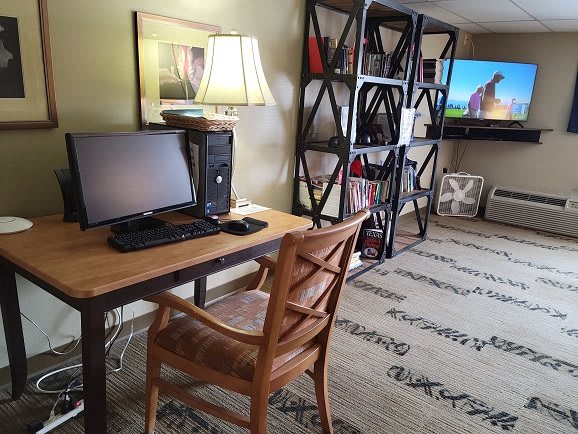 A cozy home office setup with a wooden desk, a computer, and a bookshelf.