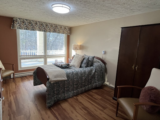 A cozy bedroom featuring a comfortable bed, wooden flooring, and ample natural light from the windows.
