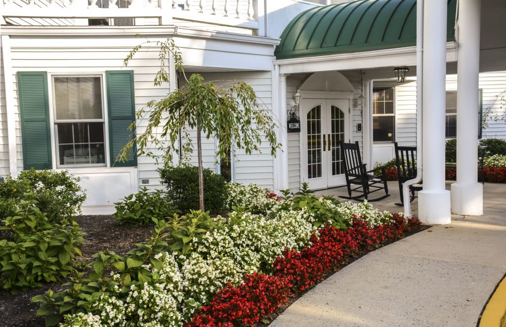 A charming house with a beautifully landscaped garden, featuring vibrant flower beds and a welcoming entrance.
