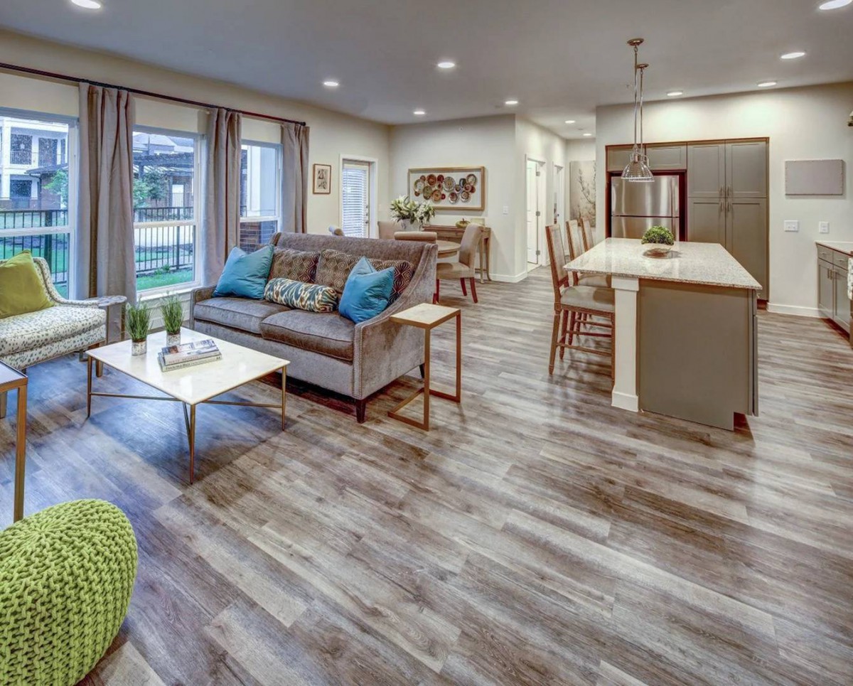 A modern open floor plan living area featuring a cozy sofa, coffee table, and adjoining kitchen with a sleek island.