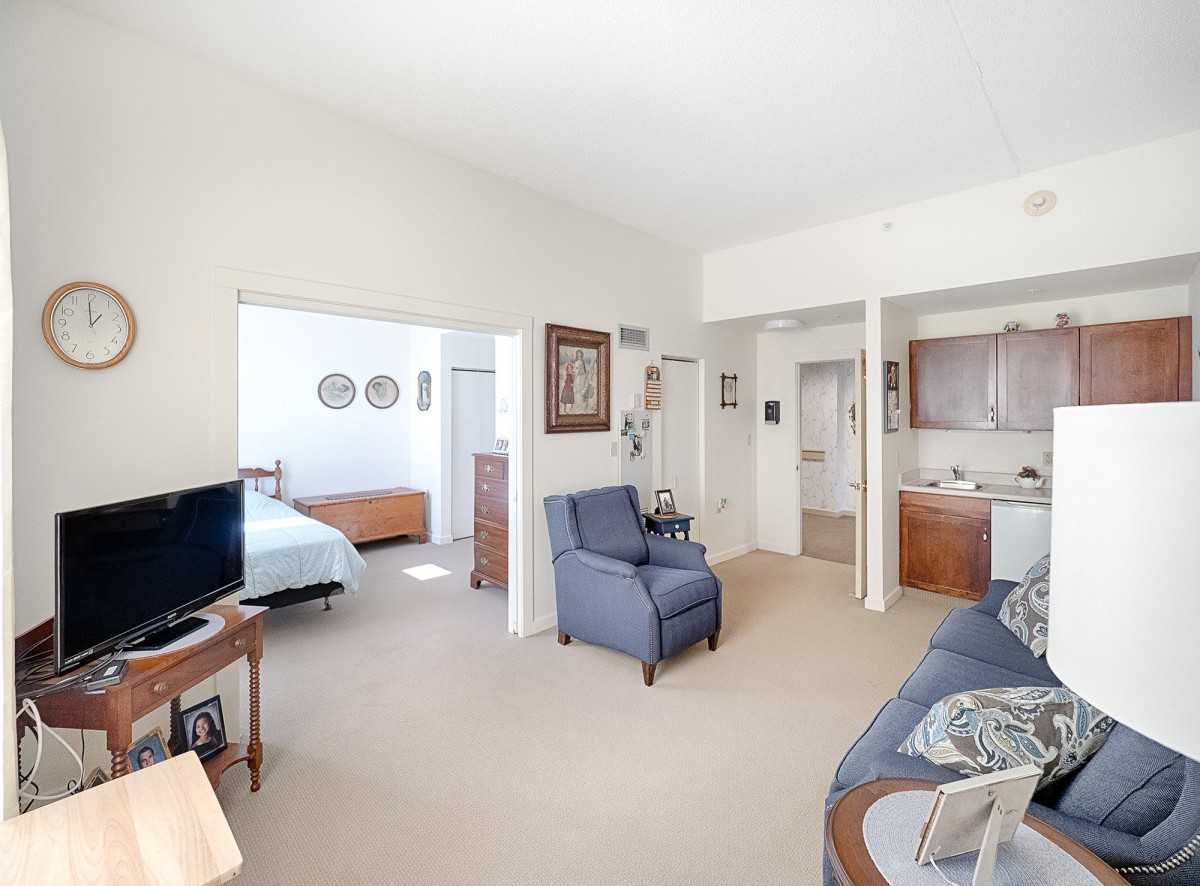 A cozy apartment living space with a view into the bedroom and a small kitchen area.