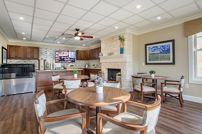A cozy dining and kitchen area featuring wooden furniture, a fireplace, and a television.