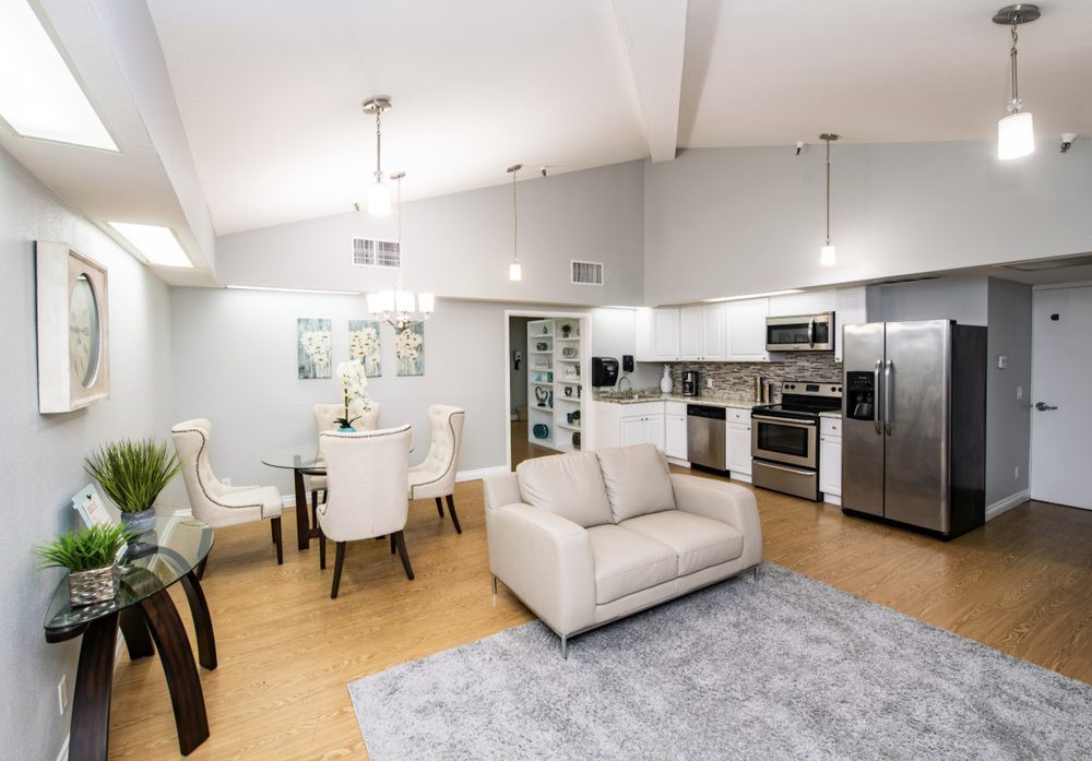 A modern open-concept living area featuring a cozy sofa, dining table, and a fully equipped kitchen.