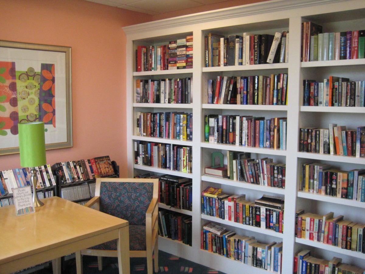 A cozy reading nook featuring a well-stocked bookshelf and a comfortable chair beside a wooden table.