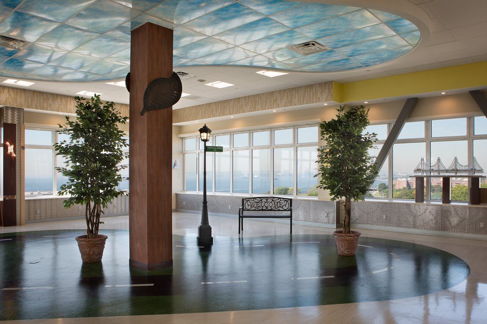 A spacious indoor atrium with potted trees, a bench, and a streetlamp under a decorative ceiling.