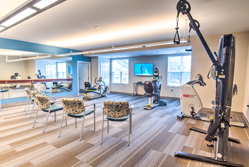 A modern indoor gym with various exercise machines and seating arrangements.