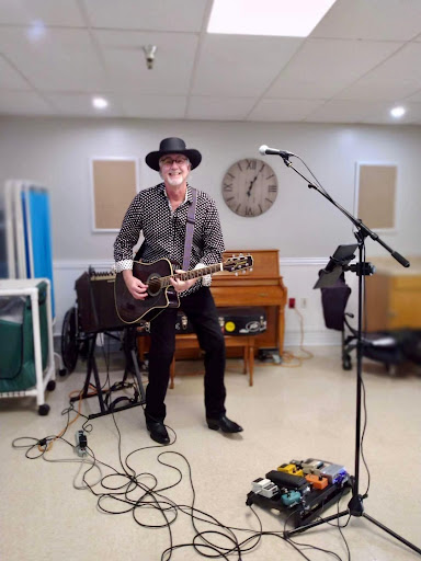 A musician performing with an acoustic guitar in a music studio setting.