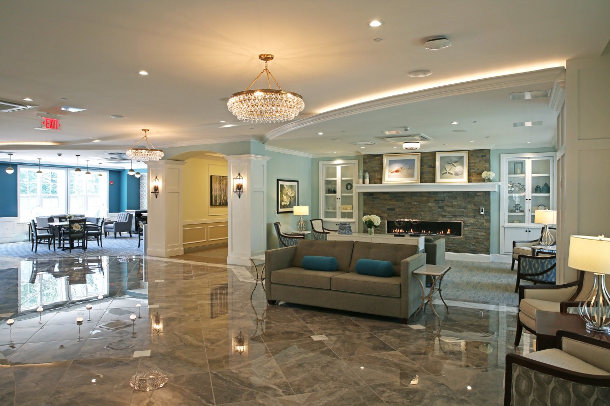 A modern lobby with a chandelier, marble flooring, and elegant furniture.