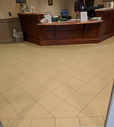 A view of a reception area featuring tiled flooring and a wooden front desk.